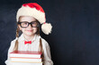 © millaf - Beautiful schoolgirl in Santa hat with book on chalk board background.