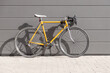 vintage yellow racing bike leaning against a gray wall