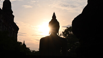 Wall Mural - Buddha silhouette in an ancient temple at sunset.