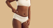 Black girl in underwear pinches belly side fat standing isolated on beige color background. Plus size woman fights excessive body weight with exercising, eating less or doing laser lipolysis procedure