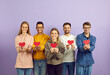 © Studio Romantic - Studio group portrait of happy positive joyful kind smiling mixed race multiethnic young people holding red paper hearts standing isolated on purple color background. Love and Valentine's Day concept