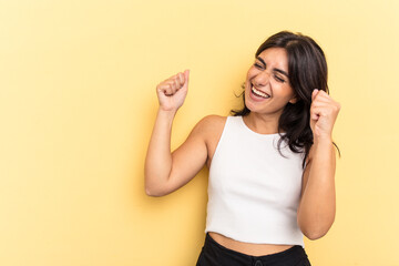 Young Indian woman isolated on yellow background raising fist after a victory, winner concept.