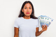 © Asier - Young indian woman holding a banknotes isolated on white background shrugs shoulders and open eyes confused.