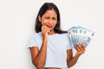 Wall Mural - Young indian woman holding a banknotes isolated on white background biting fingernails, nervous and very anxious.