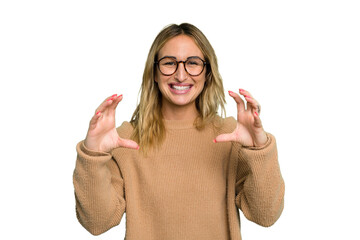 Wall Mural - Young caucasian woman isolated on green chroma background holding something with palms, offering to camera.