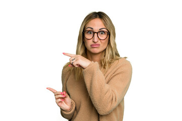 Wall Mural - Young caucasian woman isolated on green chroma background shocked pointing with index fingers to a copy space.