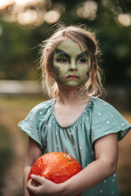 Little Girl With Witch Makeup Halloween Party With A Pumpkin