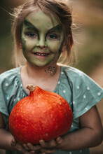 Little Girl With Witch Makeup Halloween Party With A Pumpkin