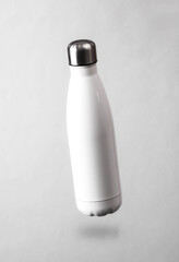 White thermal bottle levitating on a gray background with a shadow