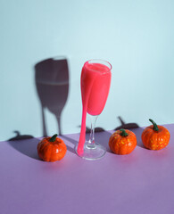 Creative halloween layout, Glass with neon slime and pumpkins on two tone pastel background. Visual trend. Minimalistic aesthetic still life. Party concept. Fresh idea