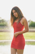 Girl with tight red dress and long straight hair posing in a park