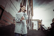 © splitov27 - Modern business woman talking on the phone while holding a folder with documents on the stairs