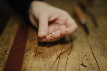 artisanal - hand sewing a leather belt	