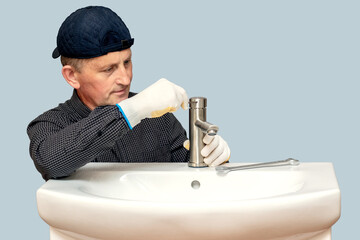 Wall Mural - The master plumber screws the faucet to the sink in the bathroom