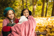 © Anastasia - Two sisters in the forest covered with a blanket are sitting next to each other. Two little sisters. Generation z. sisterhood Happy childhood.