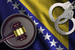 Bosnia and Herzegovina flag with judge mallet and handcuffs in dark room. Concept of criminal and punishment, background for judgement topics