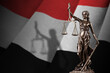 Yemen flag with statue of lady justice and judicial scales in dark room. Concept of judgement and punishment