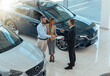 © Friends Stock - Happy beautiful couple is choosing a new car at dealership. Blurred background