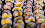Fototapeta Tęcza - Many rows of Sushi roll with seaweed, variety of Sushi roll, full fill the frame with sushi, blurred front and back, perspective view.