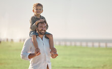 Father, Child And Summer Vacation Outdoor In Nature For Family, Love And Fun With Son On Shoulders For Happiness Portrait. Happy Dad Man And Kid Together With Smile For Time Together On Grass Field