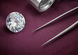 Big Round Diamond with Loupe and Tweezers on Plum Coloured Fabric Background. Luxury Diamond Photograph. 