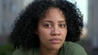 Portrait face of a young black woman looking at camera. A hispanic South American Brazilian adult girl with curly hair with natural expression
