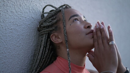 Wall Mural - One spiritual young black woman praying to God pleading help and support. A faithful Brazilian adult girl in prayer looking up at sky with HOPE and FAITH