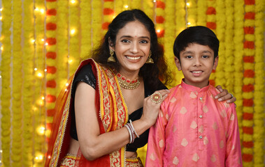 Wall Mural - Happy young woman and son celebrating diwali holding plate of diyas,gift boxes