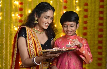 Wall Mural - Happy young woman and son celebrating diwali holding plate of diyas,gift boxes