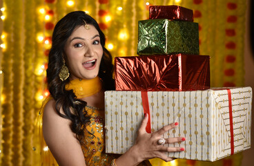 Wall Mural - Young woman holding giftboxes on diwali