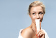 A young attractive woman with shiny and clear skin holds a tube of cream near her face. The concept of natural cosmetics for skin care.