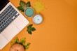 Laptop with leafs and candles on orange background. Autumn concept 