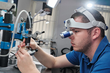 Dentist with binocular magnifying glasses working in dental clinic