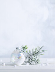 Wall Mural - christmas minimalist still life with snowy fir branches and transparent christmas ball on light back