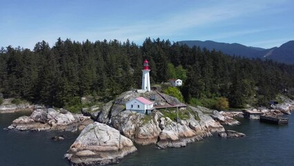 Poster - Aerial shot of a lighthouse on a rocky sea shore and in Lighthouse Park Vancouver, Canada