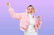 © Damir Khabirov - Young woman shouting and singing while dancing in pink bomber, glasses and ear muffs