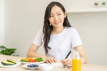 Diet, Dieting asian young woman write diet plan right nutrition on table with fresh vegetables salad, almond is different food ingredients in green. Nutritionist of healthy, nutrition of weight loss.