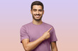 © Damir Khabirov - Young man in purple t-shirt pointing right isolated on purple background