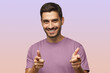 © Damir Khabirov - Young man isolated on purple background wearing t-shirt, smiling with open mouth pointing at camera