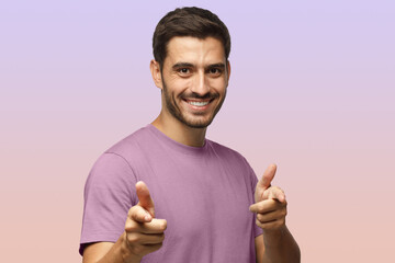 Wall Mural - young man in purple t-shirt pointing to camera with fingers isolated on purple background