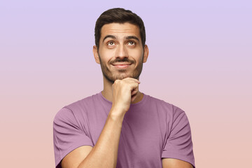 Wall Mural - Young man in t-shirt with dreamy cheerful expression, thinking, looking up, isolated on purple