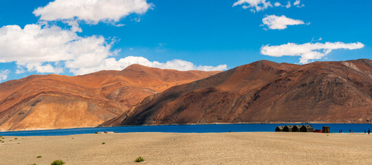 Wall Mural - Indian Army tents near Pangong Lake world’s highest saltwater lake dyed in blue stand in stark contrast to the arid mountains surrounding i