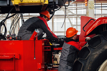 Wall Mural - Industrial workers assembles agricultural tractor in workshop