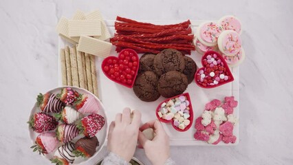 Wall Mural - Flat lay. Step by step. Arranging cheese board with candies and cookies for Valentines Day.