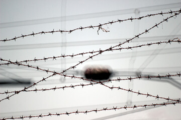 Rusty old barbed wire against a gray sky