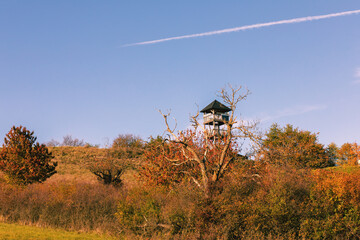 Wall Mural - Watchtower on the green meadow on a sunny day.Autumn landscape.