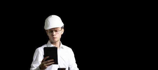 male engineer in a white helmet and a shirt in a smartphone tablet studies the building plan and documentation, architect designer on a dark background.