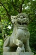 Vertical shot of Japanese stone lion statue in the park with green trees in the background