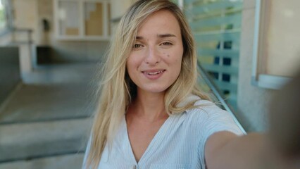 Wall Mural - Young blonde woman smiling confident having video call at street