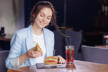 girl eating delicious sandwich close up in modern cafe